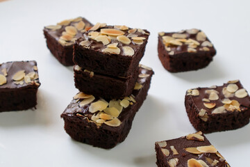 Stacked Chocolate Brownies cake with topping almond slice on white background. side view