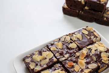 Chocolate Dessert, Chocolate Brownies with topping almond slice on plate. on white background. side view with copy space