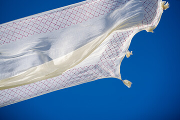 White patterned fabric blowing against a vivid blue sky