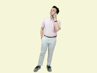 Young Asian man wearing a polo shirt and slacks, holding a mobile phone and looking at it with a...