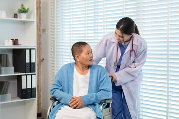 Doctor gently touching shoulder of older woman in wheelchair, expressing support, encouragement,...