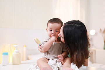 The mother dresses her child, applies powder, combs her hair and applies cream.