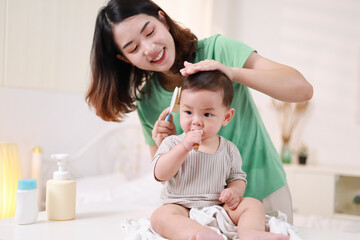 The mother dresses her child, applies powder, combs her hair and applies cream.