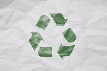 Recycling symbol drawn in green on a crumpled sheet of white paper
