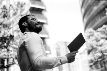 Businessman reading book outside office building, grainy analog effect