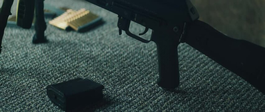 Loading ammunition magazine beside firearm on shooting mat outdoors