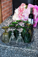 Colorful vintage wine glasses upside down on a tray with flowers and wine bottle nearby. Festive table setting ready for a celebration or elegant party.