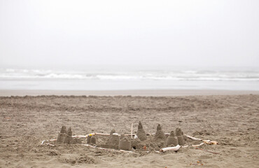 A Sand Castle Build by Children on a Beach with Fog in the Background