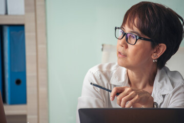 Asian Female freelance using laptop at home office desk. Woman reading financial graph chart Planning analyzing marketing data. Asian female people working office firm with business stuff, coffee cup