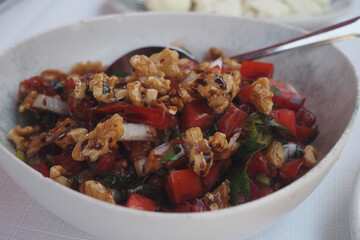 Fresh vegetable salad with nuts in a white bowl