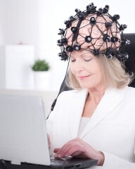 Young adult works on a laptop wearing a sleek noninvasive brain computer interface headset in a minimalist office, calm focus on device and face.