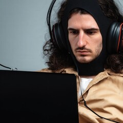 Young adult works on a laptop wearing a sleek noninvasive brain computer interface headset in a minimalist office, calm focus on device and face.