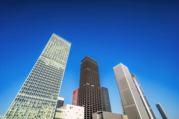 Fototapeta premium Urban Skyline: Majestic Skyscrapers Against a Bright Blue Sky