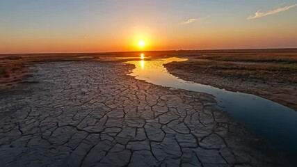 Sunrise over cracked earth and river
