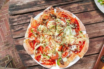 Fresh baked delicious pizza top view on wood with melted cheese, green and red bell peppers, onions...