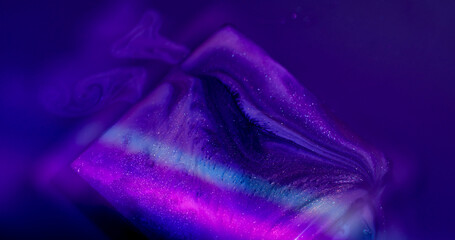 Sparkling cube. Flowing neon stripes. Defocused purple pink green color rainbow paint in water...