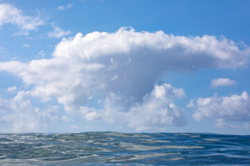 A textured cloud formation captured from the ocean's surface on a blue sky sunny day.