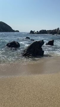 Toma a contra-luz de olas chocando en la orilla del mar en un atardecer.