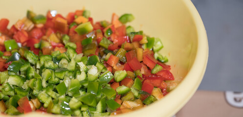 a person dicing green bell peppers on a wooden cutting board using a chef's knife. This is a common food preparation technique used in cooking for various dishes, such as stir-fries, salads, or sauces