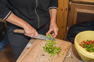 a person dicing green bell peppers on a wooden cutting board using a chef's knife. This is a common...