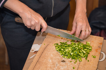 a person dicing green bell peppers on a wooden cutting board using a chef's knife. This is a common...