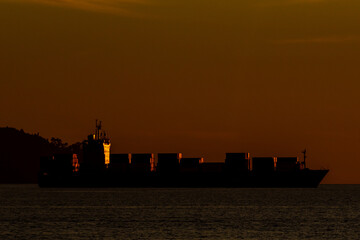 Silhouette of a container ship during sunset near Sabah, Malaysia – symbol of global maritime...