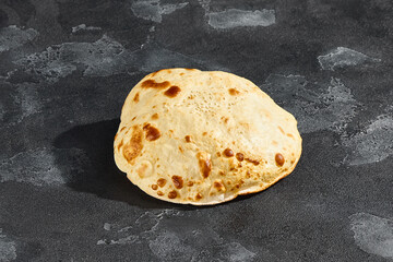 Tandoor flatbread under bright lighting, overhead composition on textured dark stone