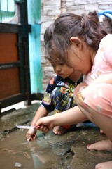 Fototapeta premium Two Little Children Playing Outdoors in a Watery Yard