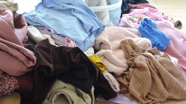 Messy laundry pile in a bright room during the day