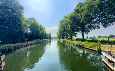A beautifully serene scene featuring a calm waterway elegantly framed by vibrant trees beneath a...