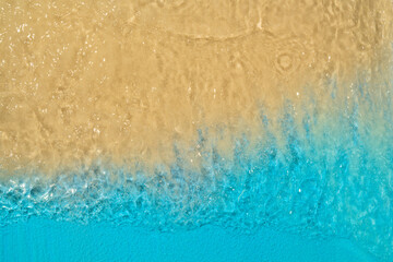 Aerial view of clean and transparent blue ocean waves on a beautiful sandy beach. Natural background. Summer concept