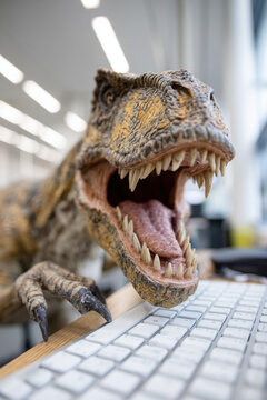 Dinosaur in office eating computer keyboard