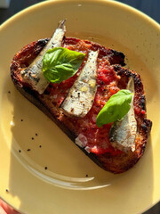 Close-up sardine toast with basil leaves.