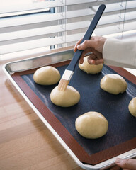 Brushing egg wash onto dough for shine.