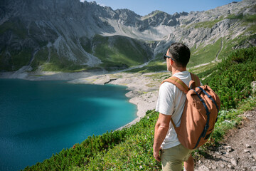 Hiker admiring breathtaking turquoise lake in the alps