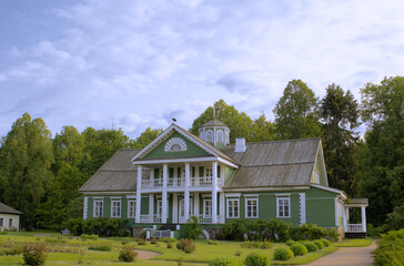 Green country house with a symmetrical structure, white columns, and high roof, set against a...