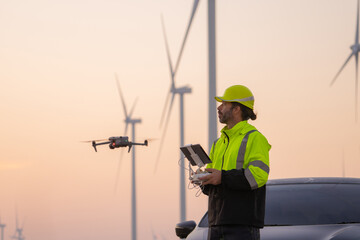 Engineers male flying drone surveying and checking wind turbines from the high angle view of the field during beautiful sunset. using drone technology for work.