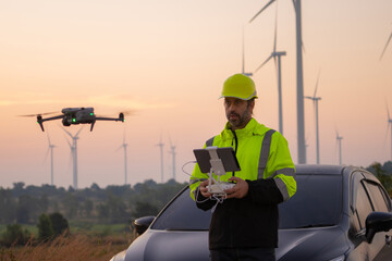 Engineers male flying drone surveying and checking wind turbines from the high angle view of the...