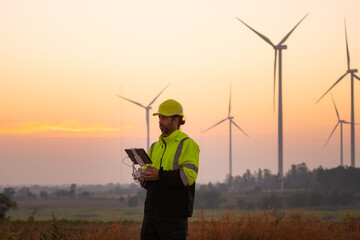 Engineers male flying drone surveying and checking wind turbines from the high angle view of the...
