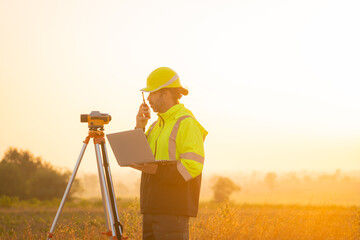 Engineer working on laptop in front of wind turbines for checking wind turbines of the field during...