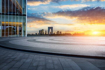 Empty square floor and modern office building with city skyline scenery at sunset in Suzhou, China.