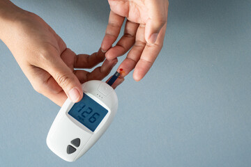 Woman's hands checking diabetes and hyperglycemia with digital blood sugar meter. Healthcare and...