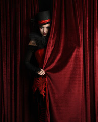 Burlesque circus performer, female model, in red corset and striped stockings in jester clown...