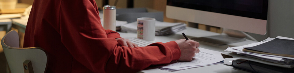 Man sitting at desk using computer and writing on documents with pen, working in scam call center...