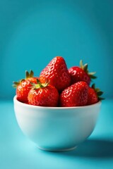 Juicy red strawberries in a white bowl, blue backdrop, natural, farm