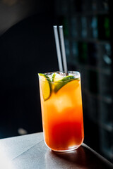 A vibrant cocktail with layers of color sits on a sleek bar counter, beckoning to be enjoyed