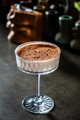 A stunning dessert sits elegantly in a glass, showcasing creamy layers topped with cocoa powder