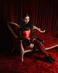 Burlesque circus performer, fantasy female model in gothic halloween jester clown costume with top...
