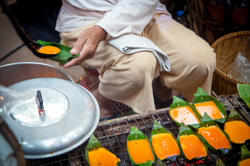 "A rural street vendor skillfully grills seasoned eggs,
