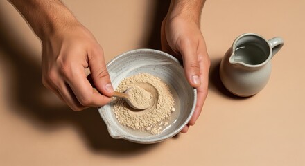 Fototapeta premium Hands mixing powder and water in ceramic bowl with pitcher nearby